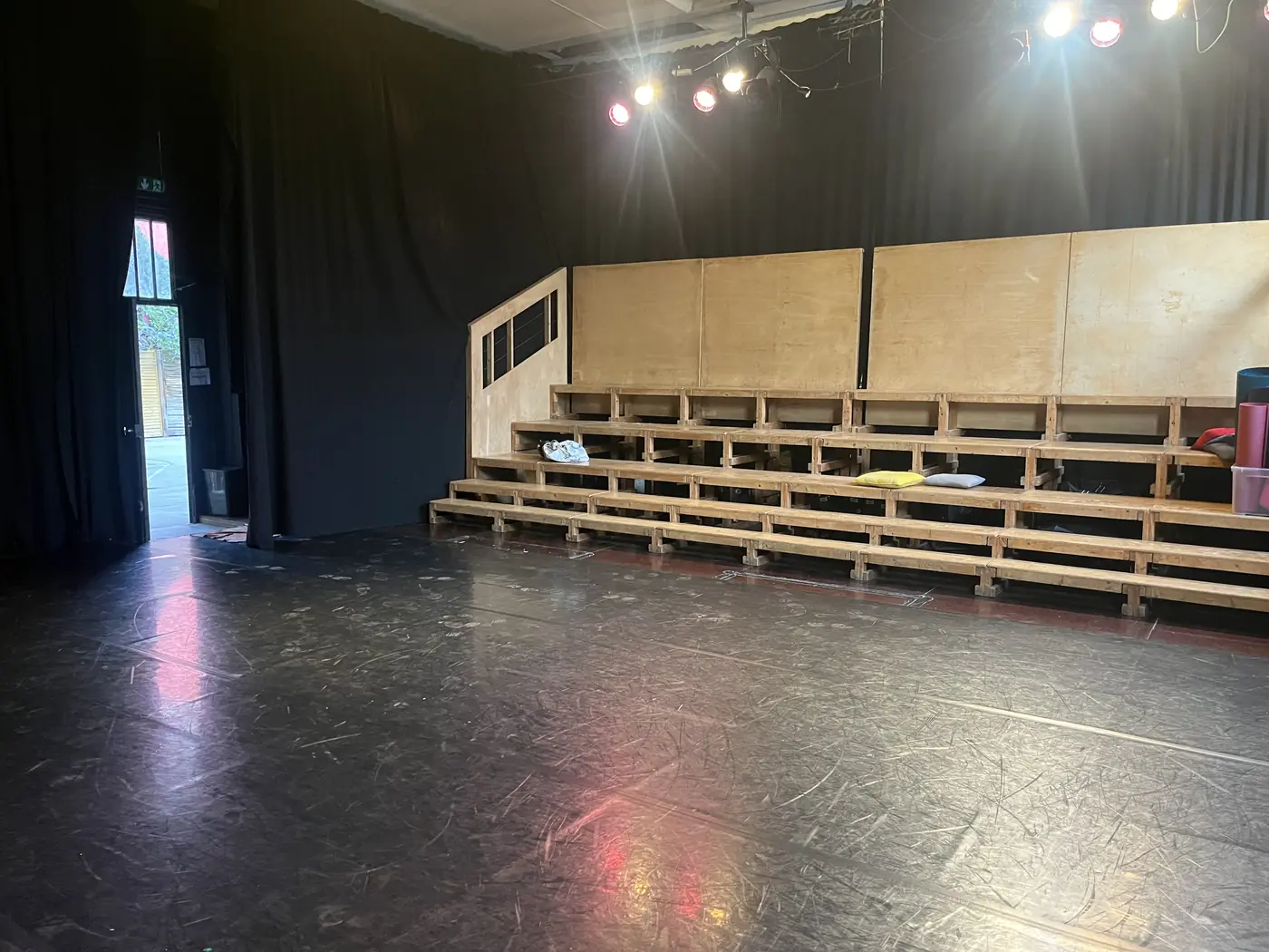 La salle de La Fonderie&nbsp;: plateau au sol noir, gradins de bois, projecteurs allumés.