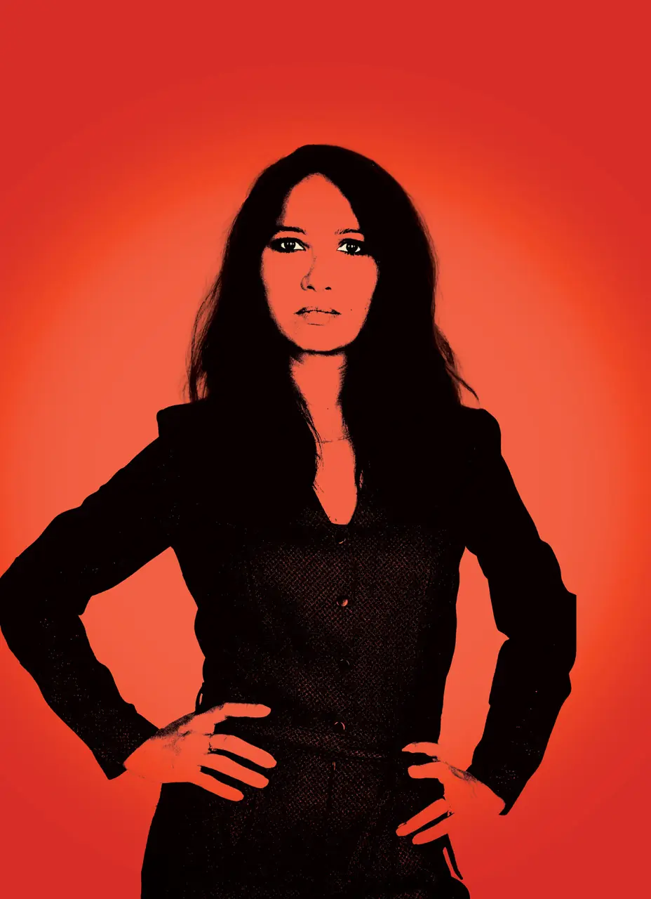 Affiche de CORIACE : Andréa Brusque, vêtue de noir, mains sur les hanches, découpée sur un aplat rouge incandescent.